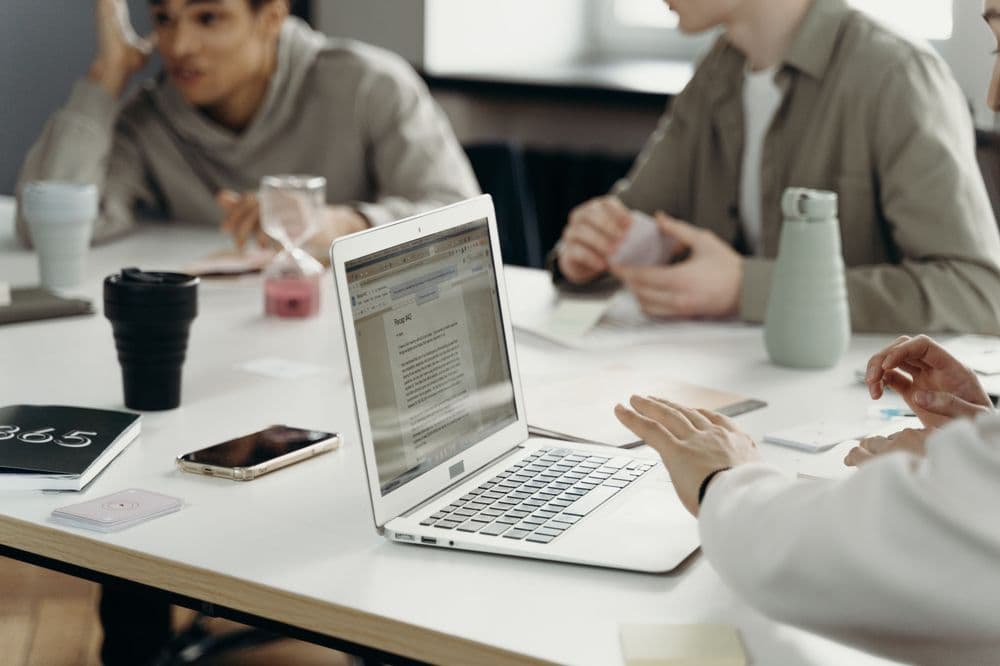 Equipo de trabajo colaborando alrededor de una laptop en una oficina flexible