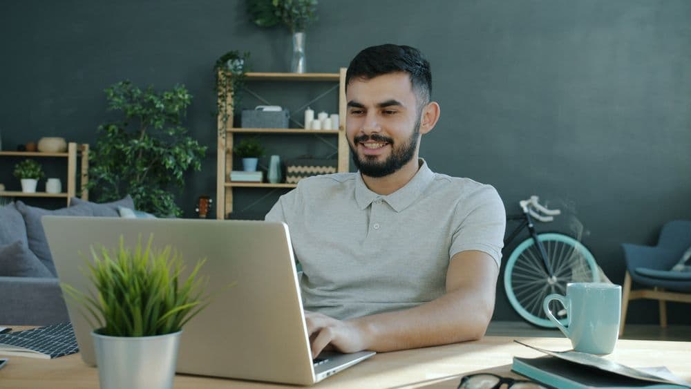 Persona trabajando desde casa con una laptop en un espacio de home office
